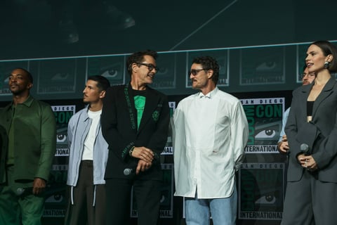 Five men standing together at what appears to be a panel event or press conference with green-tinted background and signage