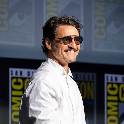 Man wearing sunglasses and white shirt smiling at Comic-Con panel event